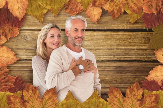 Cheerful wife embracing husband against wooden background