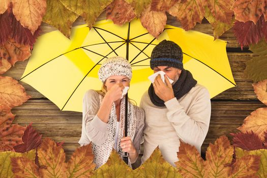 Couple sneezing in tissue while standing under umbrella against wooden background