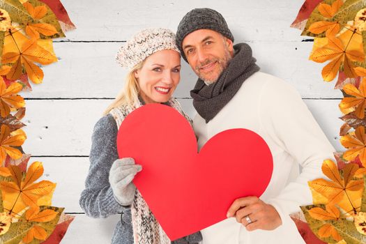 Portrait of happy couple holding heart against white wood