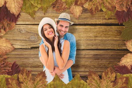Happy hipster couple smiling at camera against wooden background