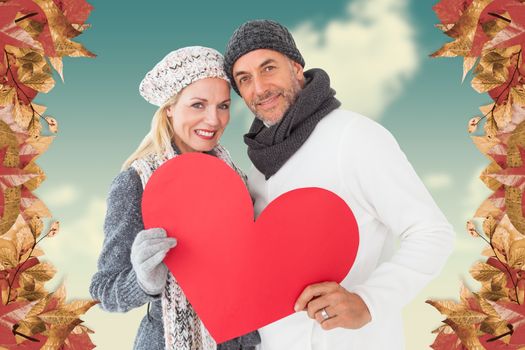 Portrait of happy couple holding heart against blue sky