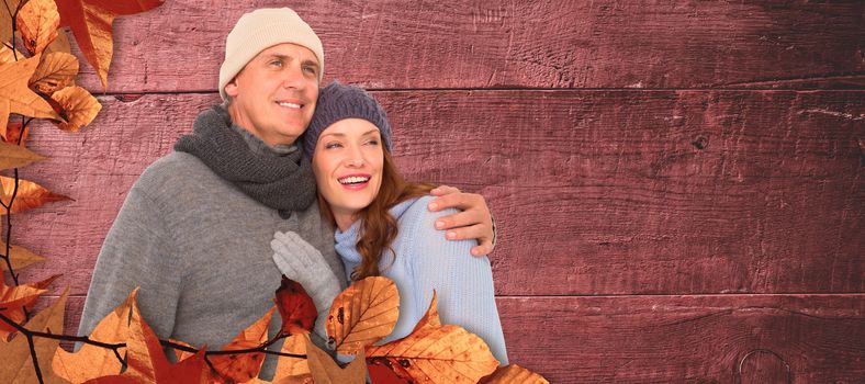 Couple in warm clothing embracing against overhead of wooden planks