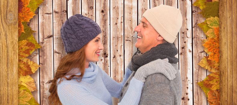 Happy couple in warm clothing against wooden planks background