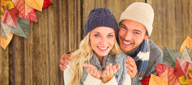 Attractive couple in winter fashion smiling at camera against close-up of wooden plank