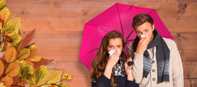 Couple blowing nose while holding umbrella against bleached wooden planks background