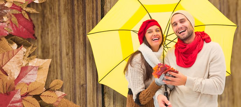 Autumn couple holding umbrella against close-up of wooden plank