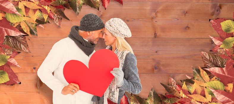 Couple holding heart while looking at each other against bleached wooden planks background