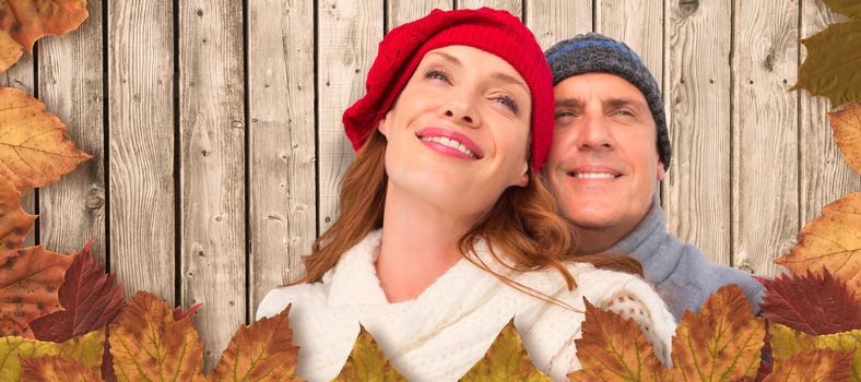 Happy couple in warm clothing against digitally generated grey wooden planks