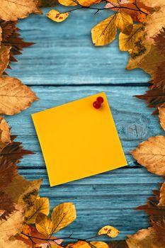 Digital image of pushpin on yellow paper  against autumn leaves pattern