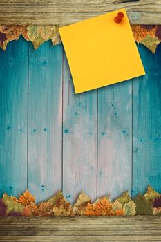 Digital image of pushpin on yellow paper  against autumn leaves pattern