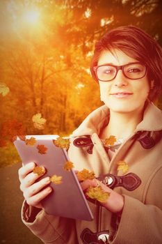 Portrait of beautiful woman using tablet PC against autumn scene