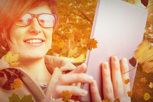 Portrait of smiling woman in glasses using tablet computer against autumn scene