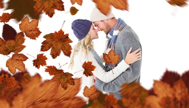 Attractive couple in winter fashion hugging against autumn leaves