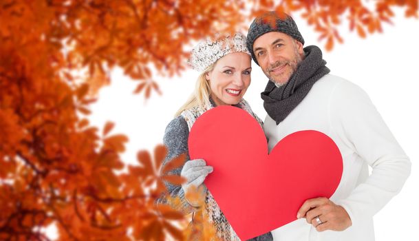 Portrait of happy couple holding heart against autumn leaves