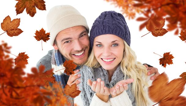 Attractive couple in winter fashion smiling at camera against autumn leaves