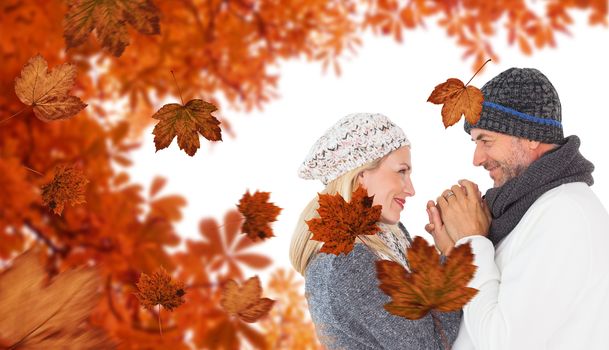 Cute smiling couple holding hands against autumn leaves pattern