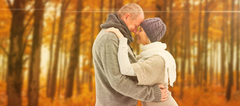 Happy mature couple in winter clothes embracing against autumn scene