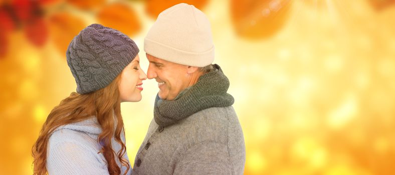 Couple in warm clothing facing each other against autumn scene