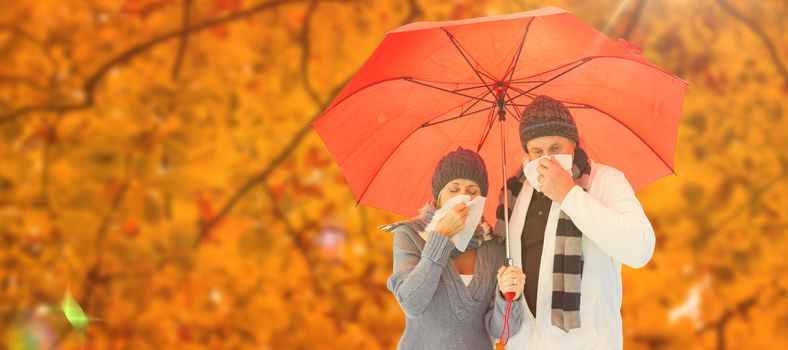 Mature couple blowing their noses under umbrella against autumn scene