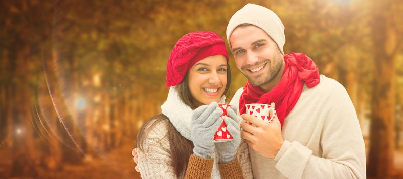Winter couple holding mugs against autumn scene