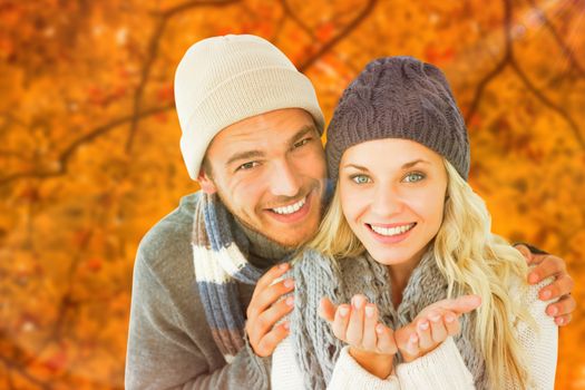 Attractive couple in winter fashion smiling at camera against autumn scene