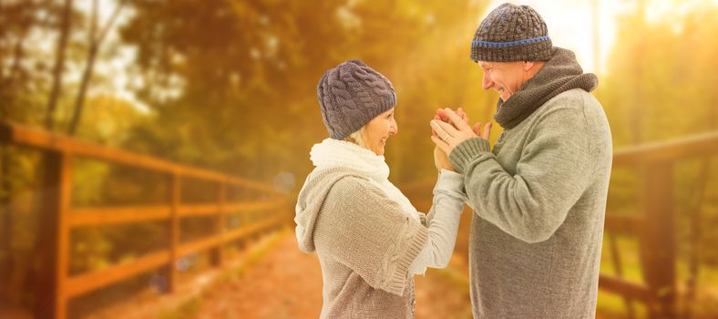 Happy mature couple in winter clothes embracing against autumn scene