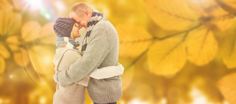 Happy mature couple in winter clothes hugging against autumn scene