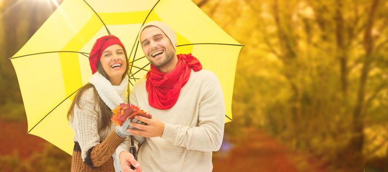 Autumn couple holding umbrella against peaceful autumn scene in forest
