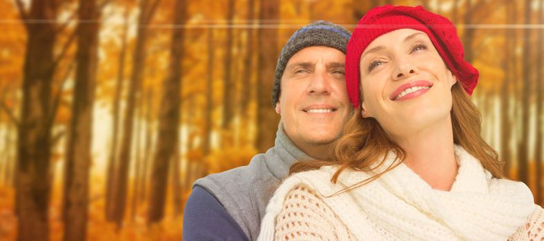 Happy couple in warm clothing against autumn scene