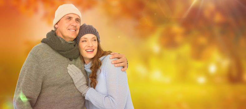 Couple in warm clothing embracing against autumn scene