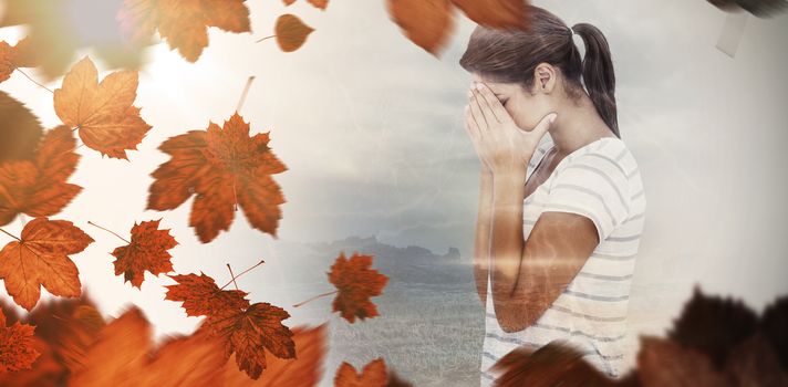 Side view of upset woman covering face against autumn leaves