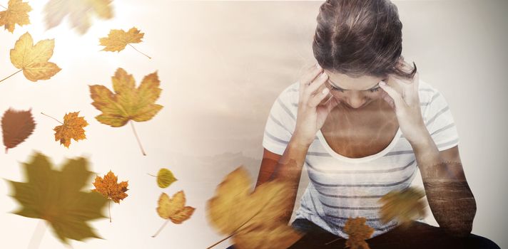 Pretty brunette with head on hands  against autumn leaves