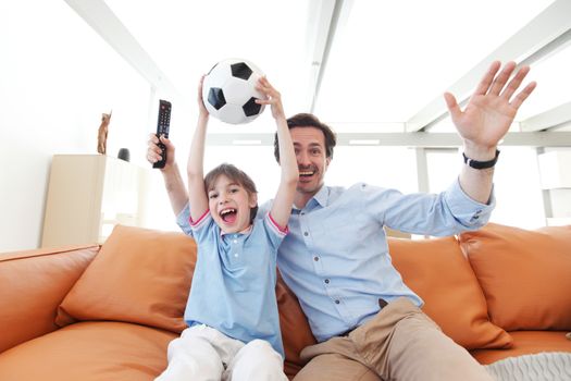 father and son wathcing football inside their house