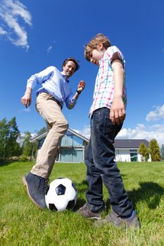 father and son playing football in front of their house