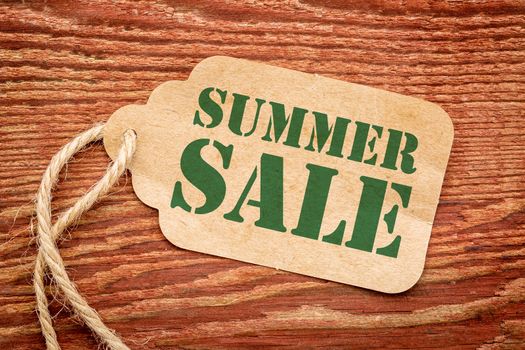 summer sale sign - a paper price tag against rustic red painted barn wood