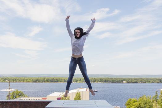 Photo of jumping young woman on river background