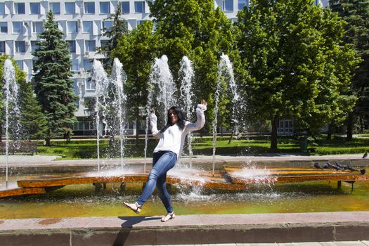 Jumping Caucasian brunette woman on fountain background