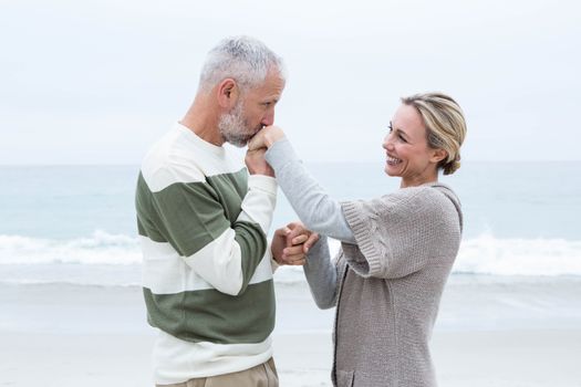 Romantic man kissing womans hand at the beach