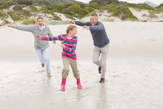 Parents chasing their kid for fun at the beach