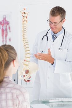 Doctor explaining anatomical spine to his patient in medical office 
