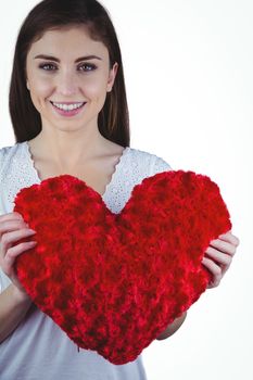 Woman holding heart shape cushion on white background