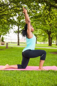 Young woman doing yoga on mat in the park