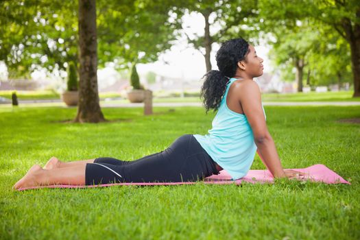 Young woman doing yoga on mat in the park