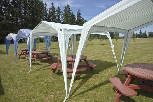 Picnic tables and tent gazebos on an outdoor lawn Canby Oregon.