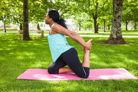 Young woman doing yoga on mat in the park