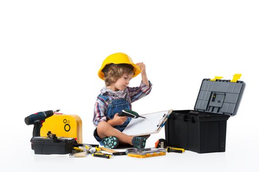 Little boy dressed as utility worker with protective helmet trying to figure out how the drill works