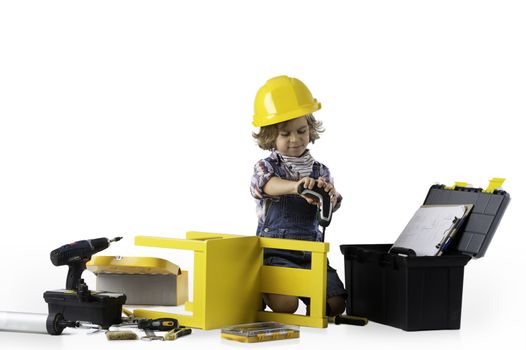 Little boy dressed as utility worker with protective helmet using electric drill