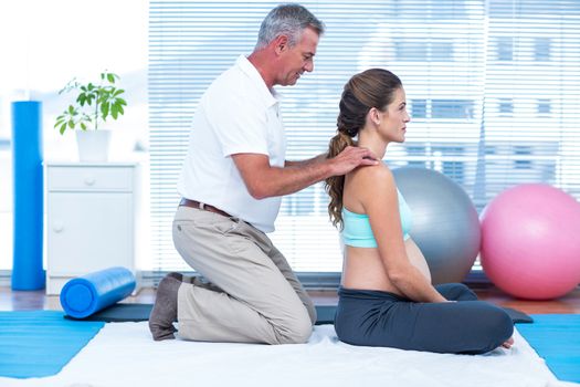 Side view of gym trainer massaging pregnant woman 
