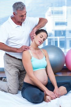Pregnant woman exercising in gym with trainer