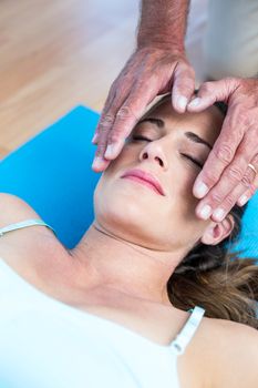 High angle view of relaxed woman getting reiki treatment in health club